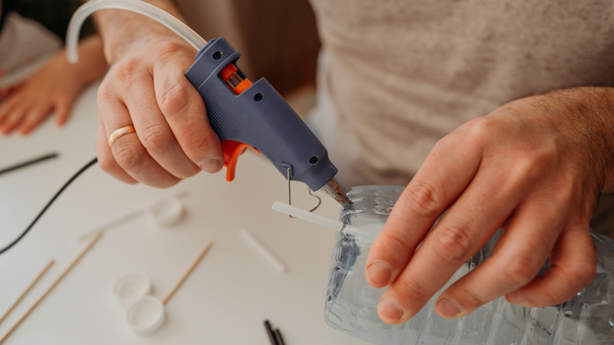 Hände kleben eine Plastikflasche zusammen