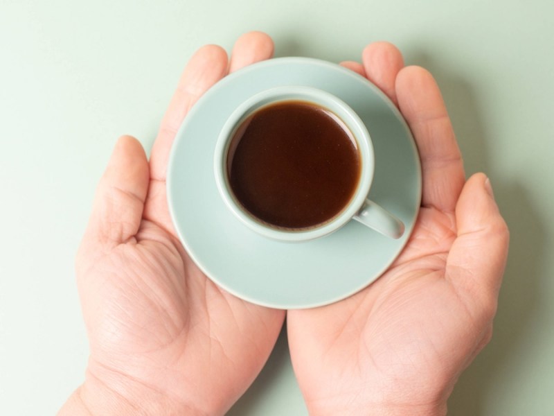 Kleine Tasse Kaffee in den Händen halten.