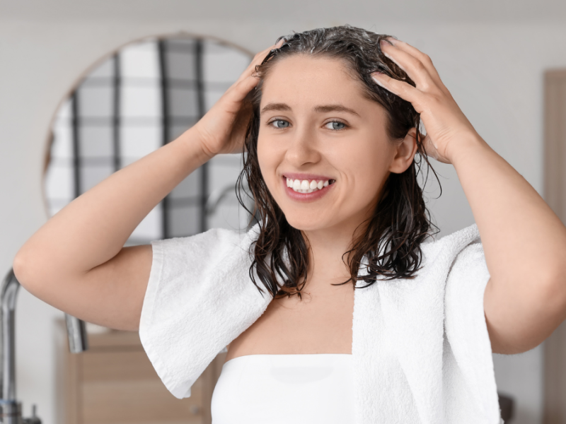 Eine Frau massiert Shampoo in ihre Haare.