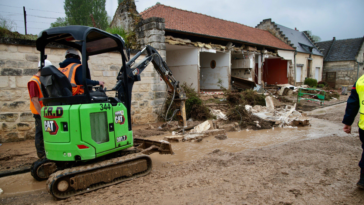 Ein Bagger vor einem zerstÃ¶rten Haus.