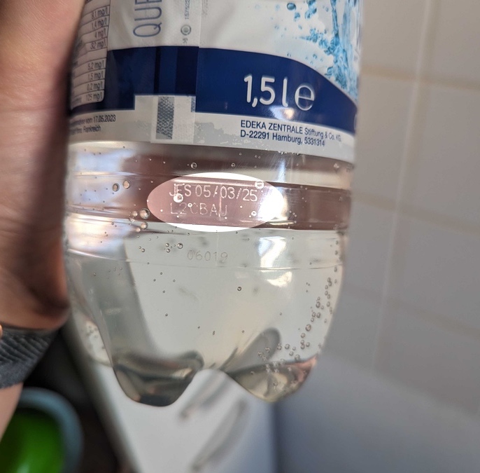 Das eingeprägte MHD einer Mineralwasserflasche.