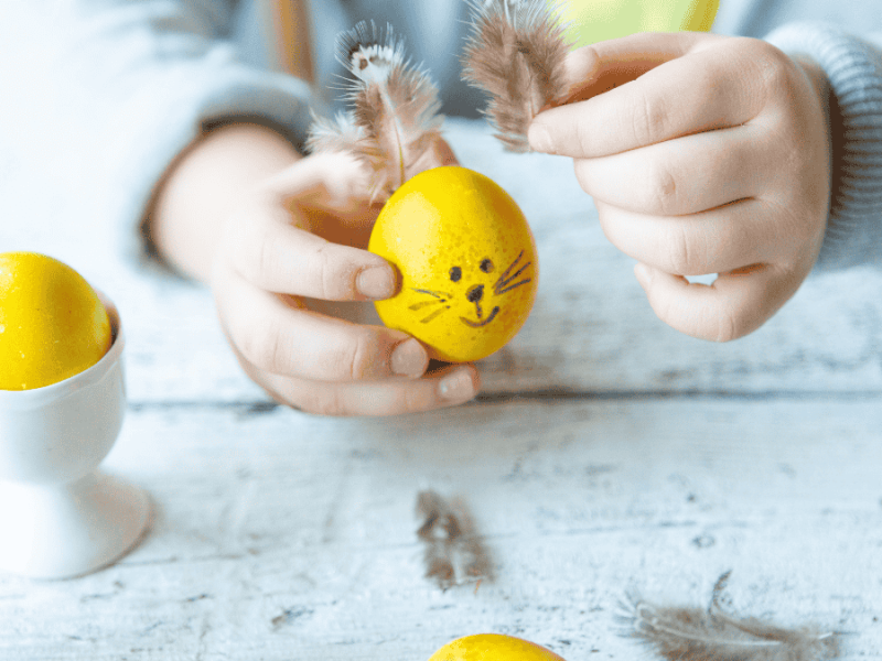Osterdeko basteln, Kind beklebt gelbes Ei