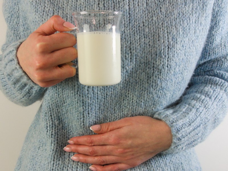 Eine Frau hat schlechte Milch getrunken und hält sich den Bauch.