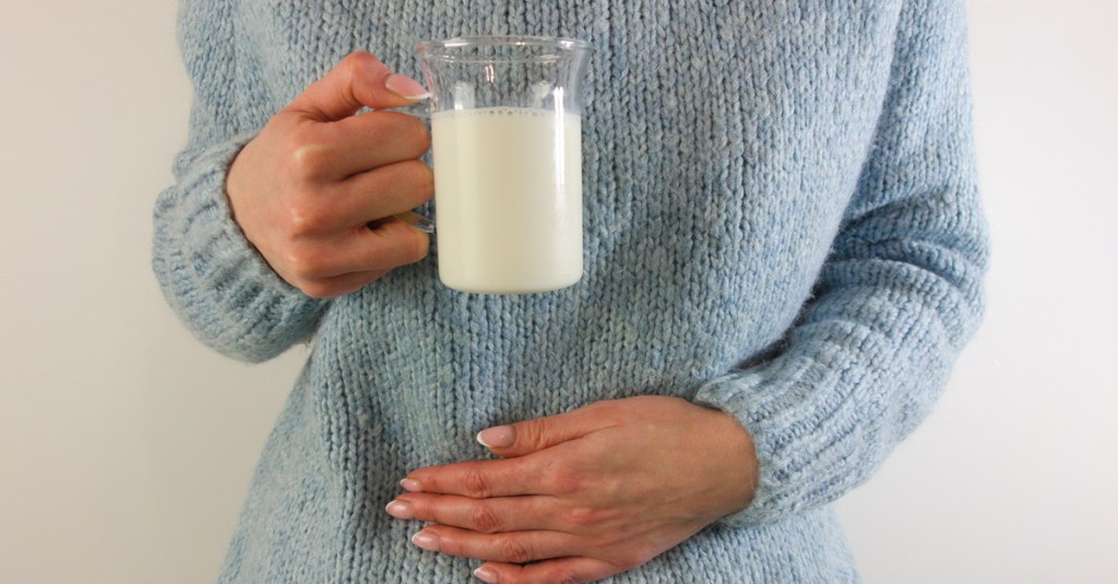 Eine Frau hat schlechte Milch getrunken und hält sich den Bauch.