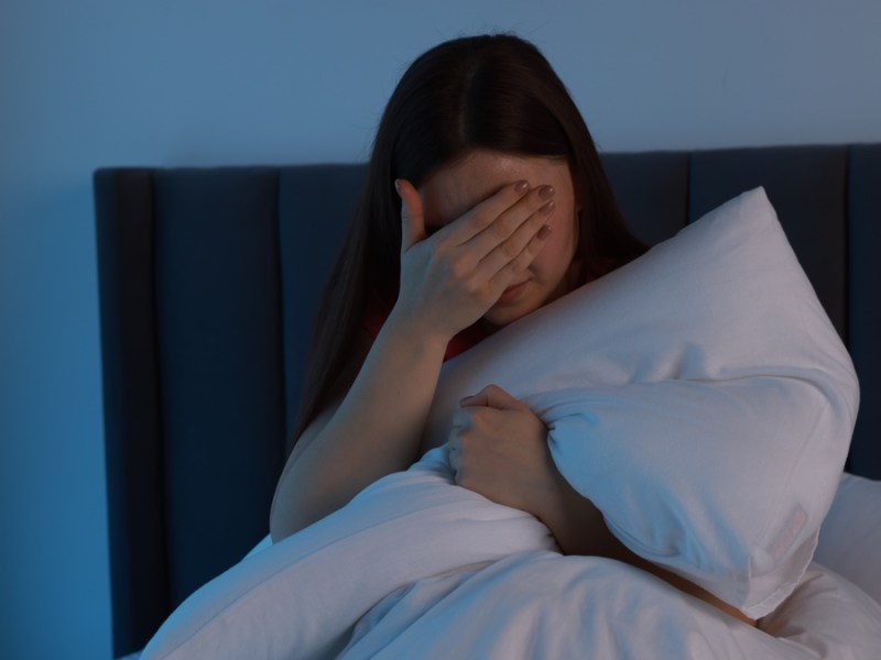 Frau sitzt nachts wach in ihrem Bett.