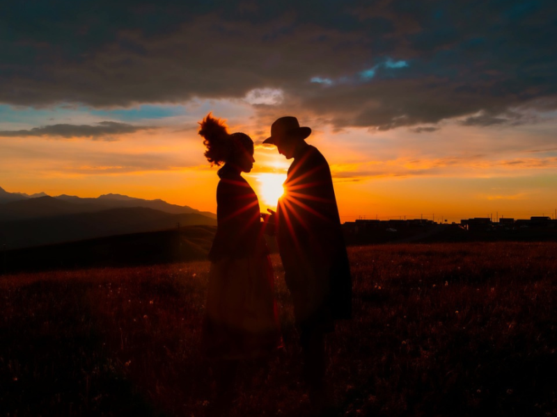 Zwei Personen stehen vor einem Sonnenuntergang.