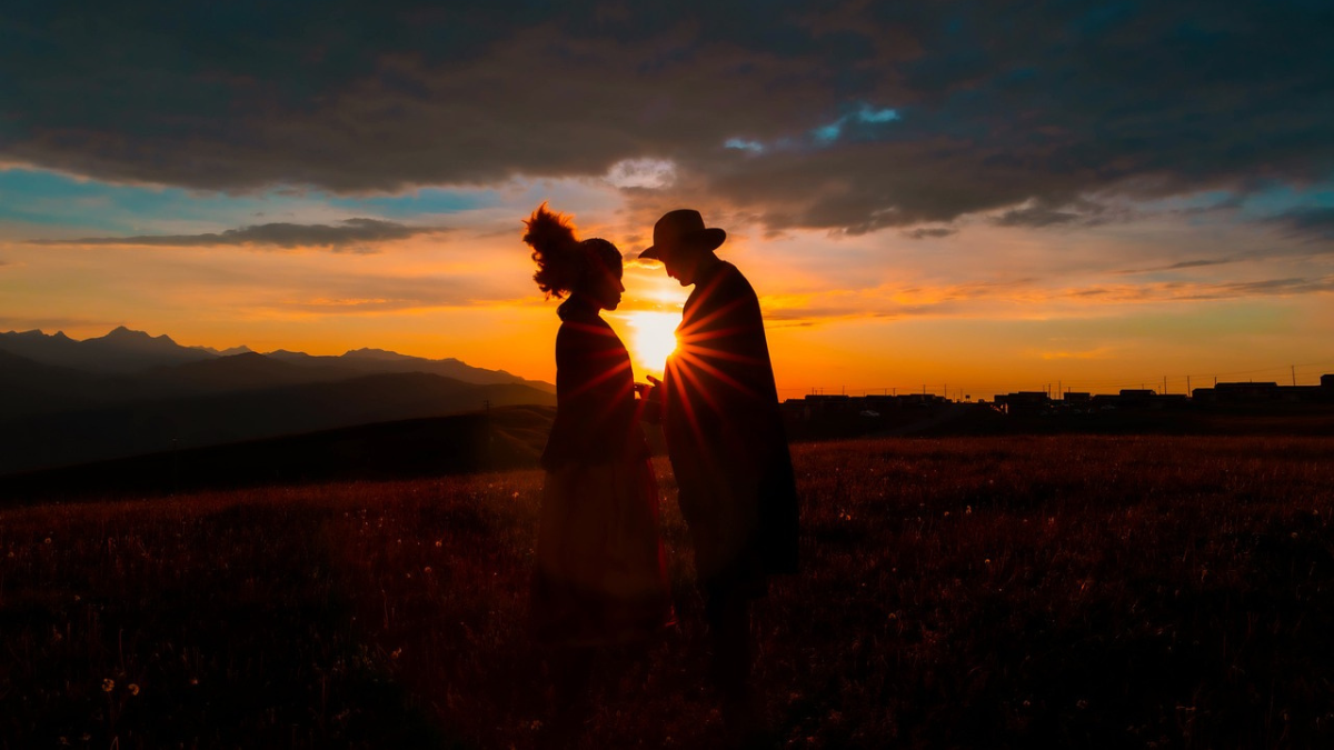 Zwei Personen stehen vor einem Sonnenuntergang.