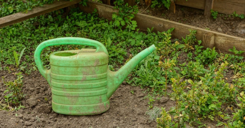 Verdreckte Kunststoff-Gießkanne im Garten