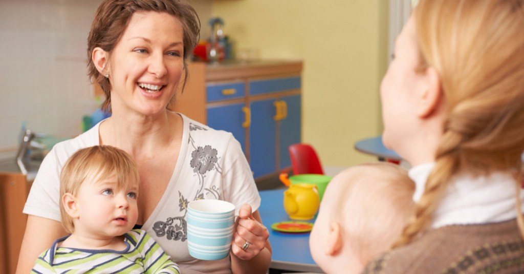 zwei Mütter mit Babys trinken Kaffee und unterhalten sich