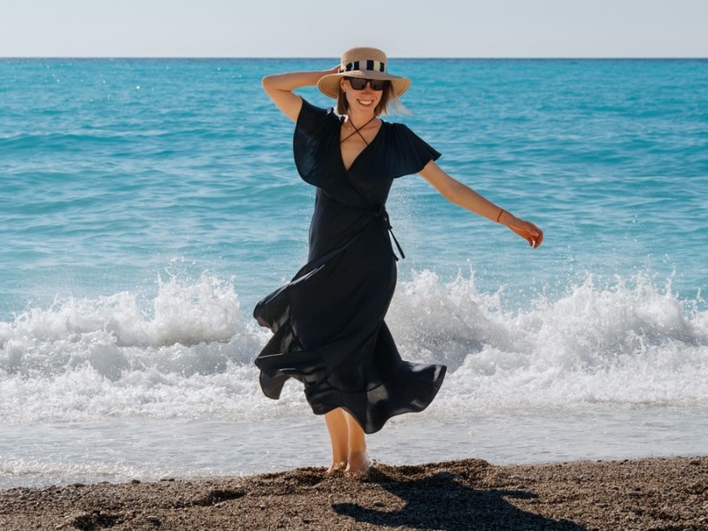 Frau in schwarzem Kleid am Meer.