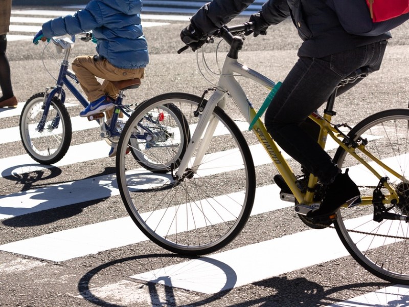 Fahrradfahrer überqueren auf dem Fahrrad sitzend einen Zebrastreifen.