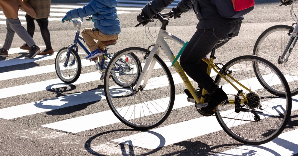 Fahrradfahrer überqueren auf dem Fahrrad sitzend einen Zebrastreifen.