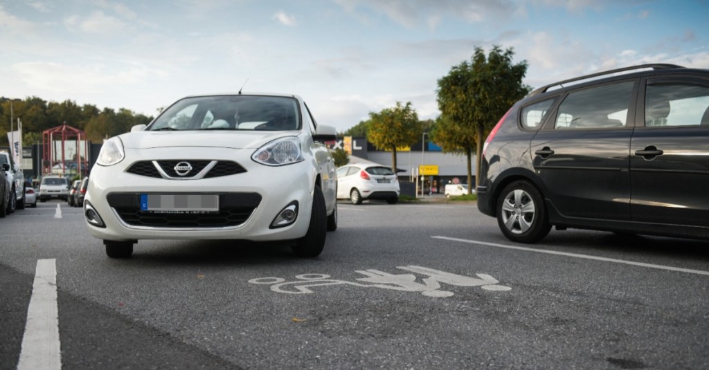 Ein weißes Auto fährst auf einen Mutter-Kind-Parkplatz.