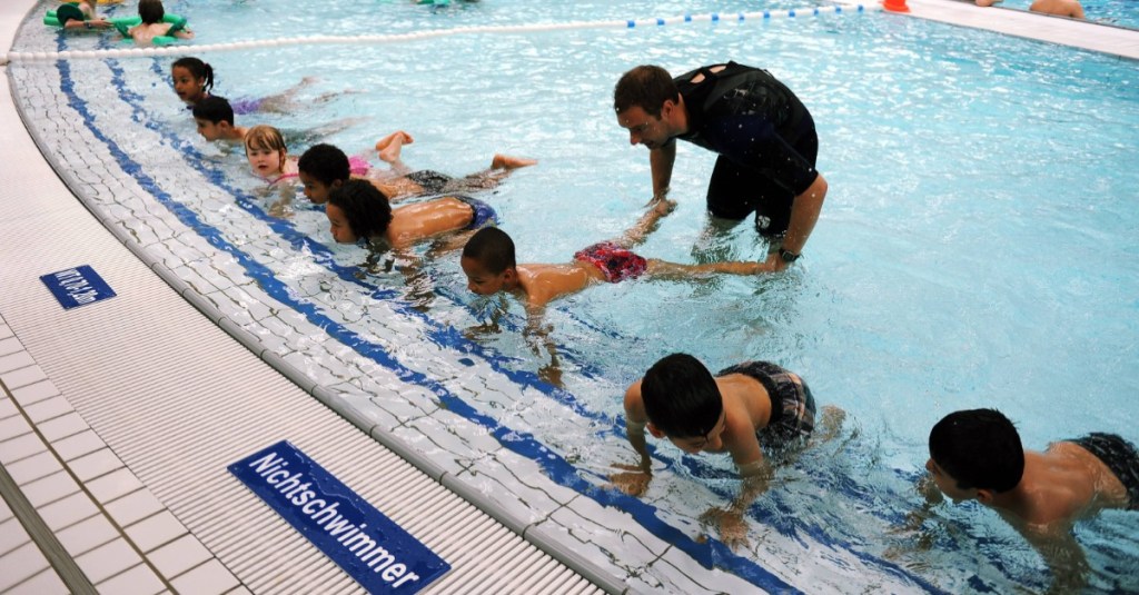 Kinder und ein Schwimmlehrer in einer Schwimmhalle