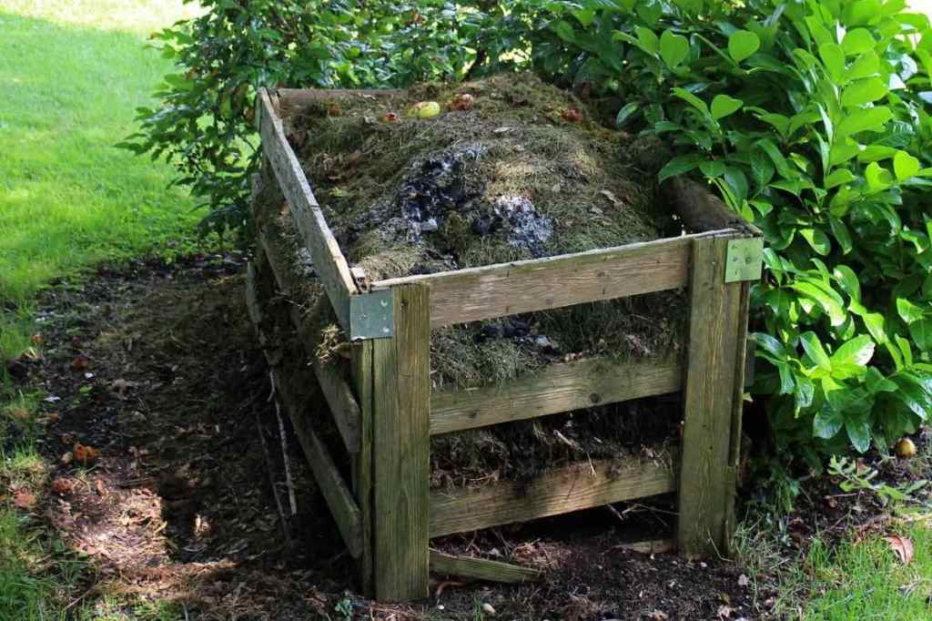 Ein selbst gebauter und angelegter Kompost in einem grünen Garten.