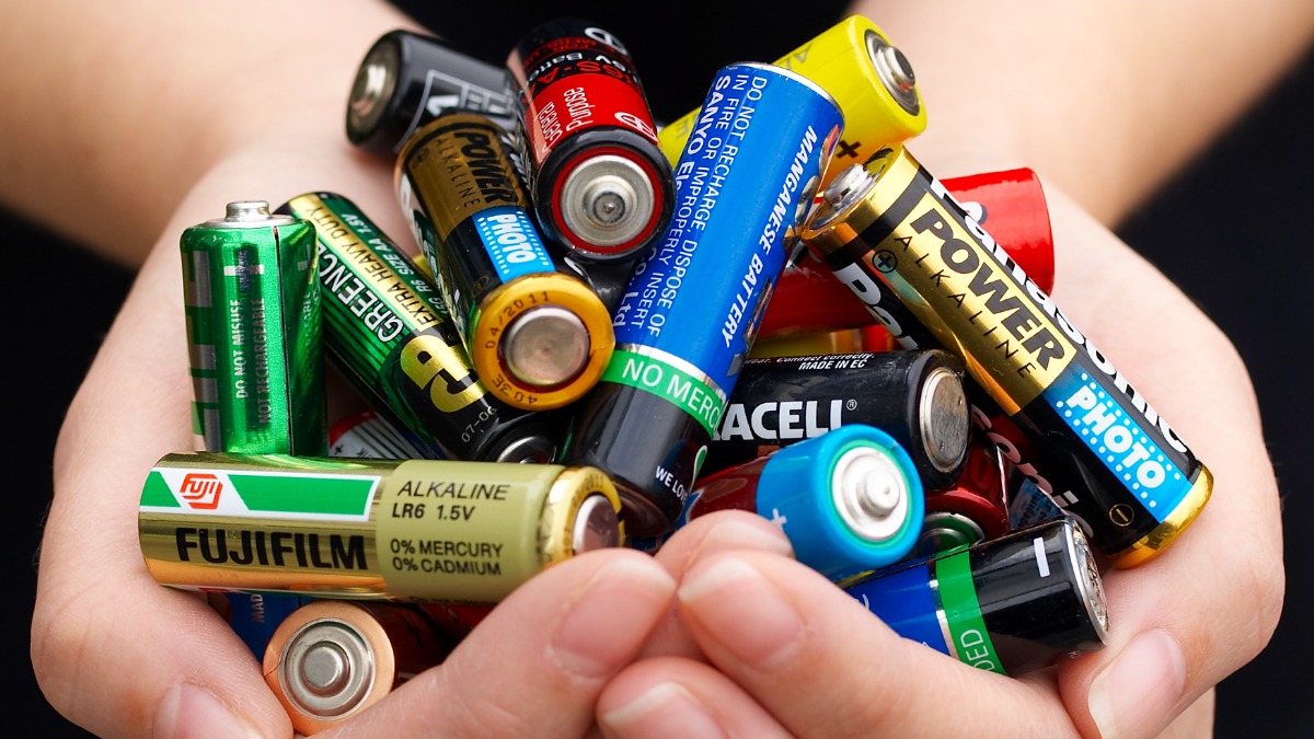 Zwei Hände halten viele Batterien