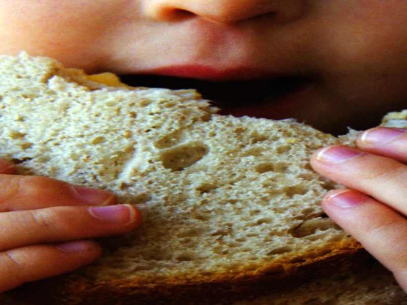 Ein Kind isst eine Scheibe Brot.