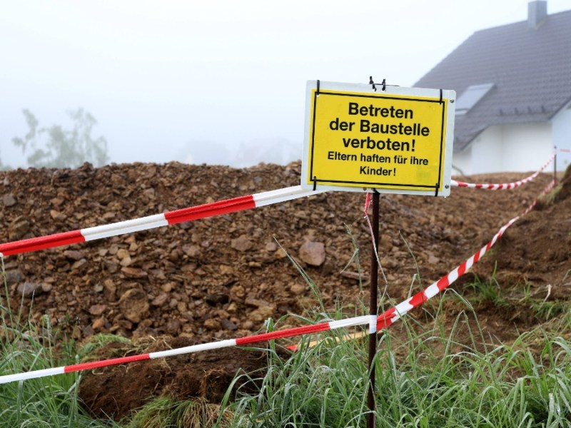 Schild mit der Aufschrift "Eltern haften für ihre Kinder" vor einer Baustelle