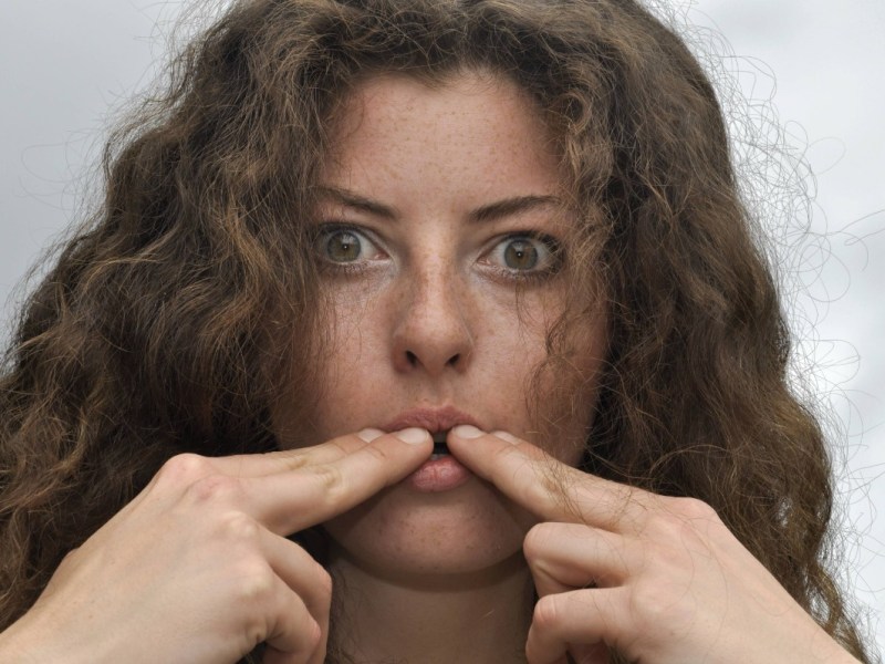 Eine junge Frau beim Pfeifen mit Finger.