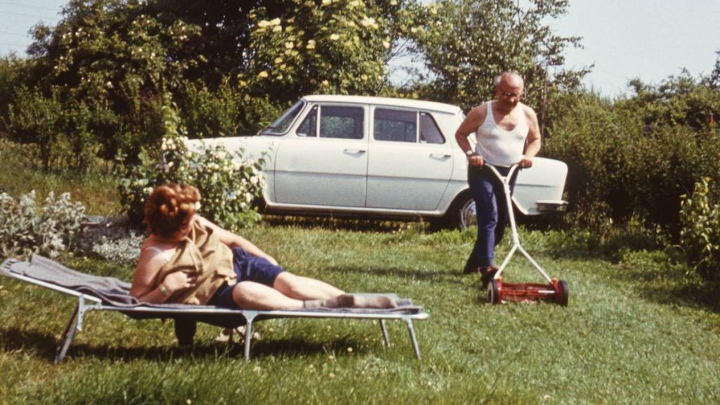 Foto von früher zeigt älteren Mann, der den Rasen mäht.