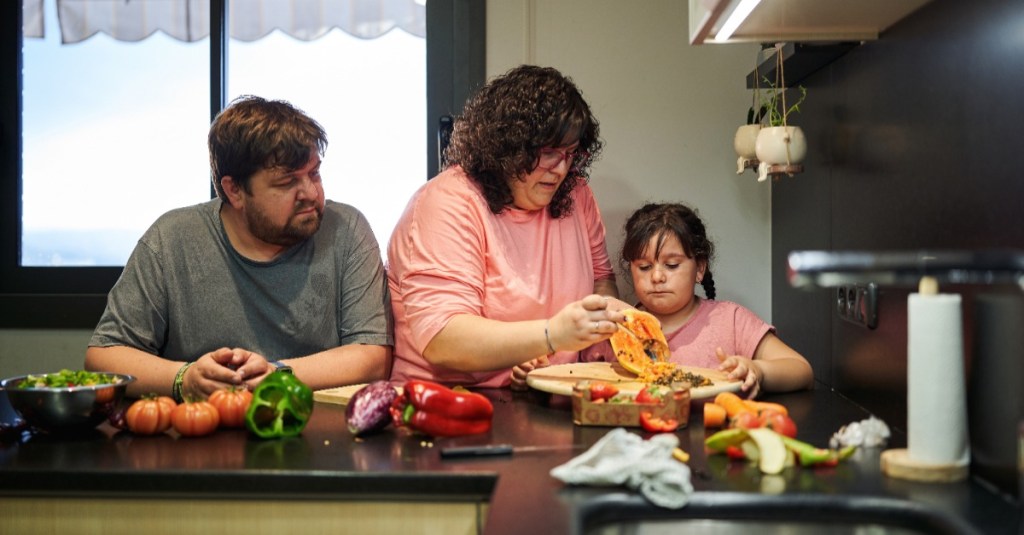 Eine glückliche, etwas kräftigere Familie bereitet sich Essen zu.