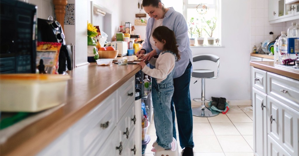 Mutter und Tochter stehen in der Küche und bereiten Essen zu 