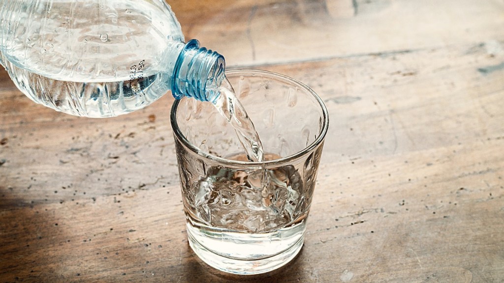 ein Glas, in das Wasser aus einer Flasche gefüllt wird