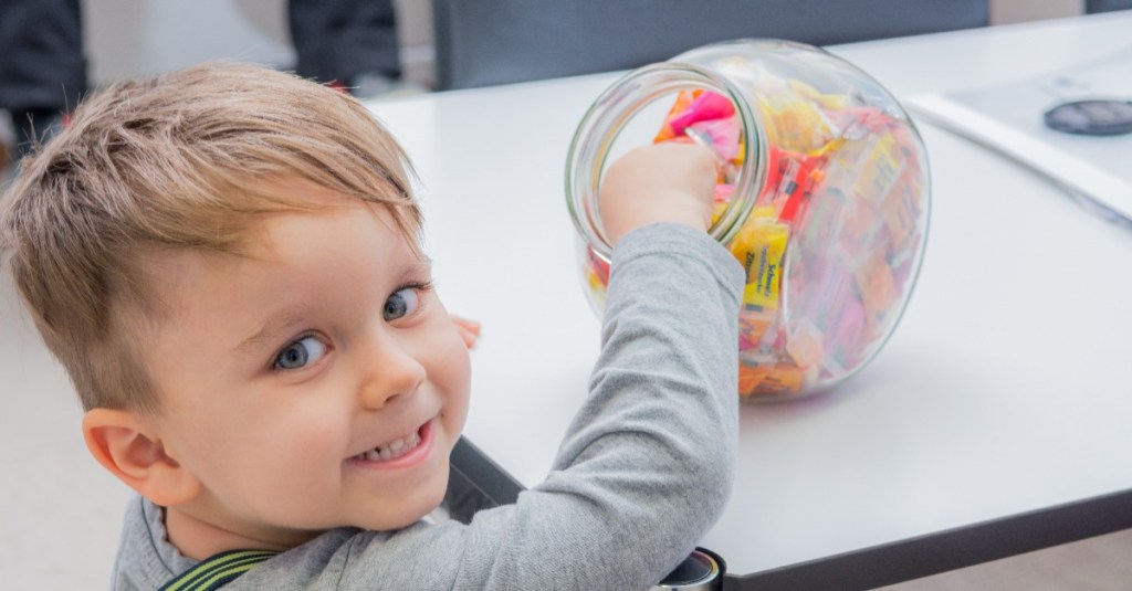 Kind nimmt Bonbons aus einem Vorratsglas