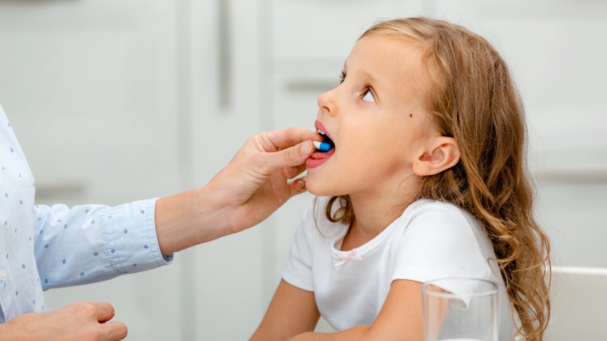 Vitaminpräparate für Kinder: Ein Mädchen hat eine Tablette im Mund