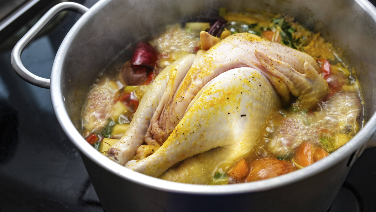 Hühnersuppe mit ganzem Huhn und Gemüse in einer Brühe