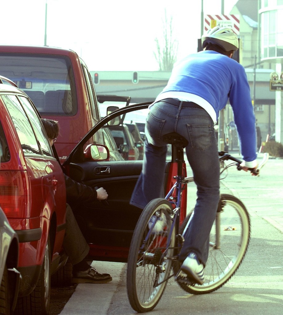 ein Fahrradfahrer fährt gegen eine geöffnete Beifahrertür