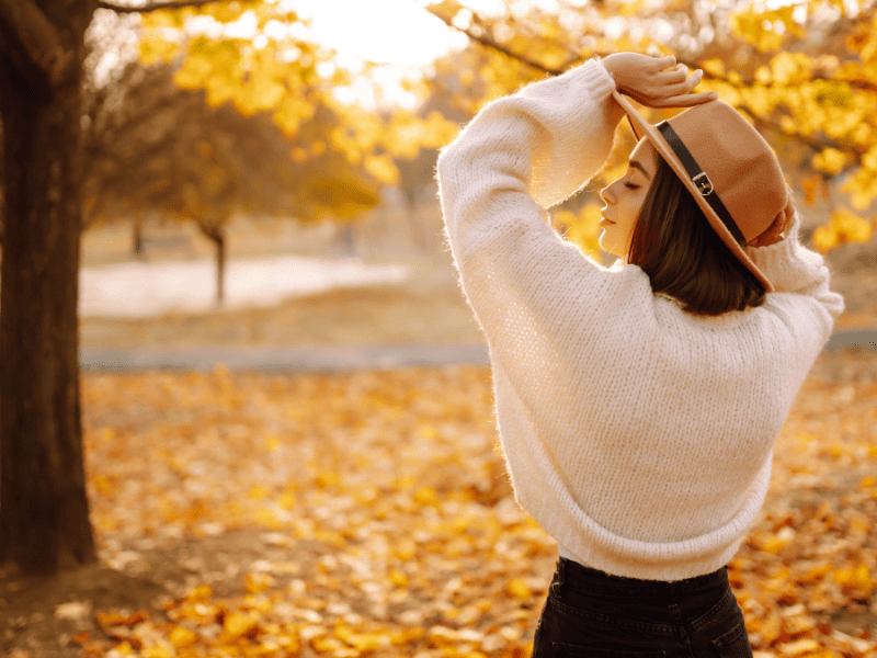 Eine Frau mit Hut in einer herbstlichen Landschaft.