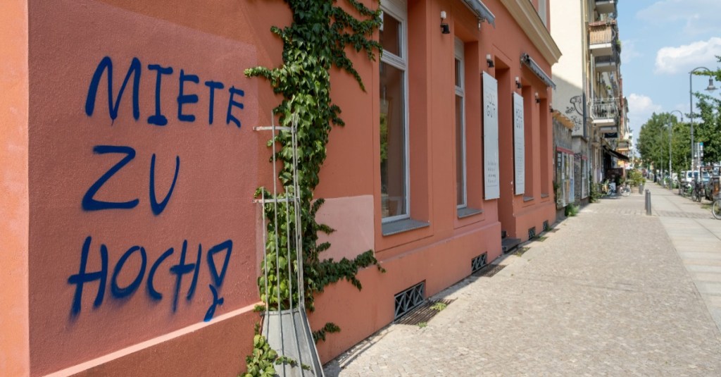 jemand hat auf eine rote Hauswand "Miete zu hoch!" geschrieben