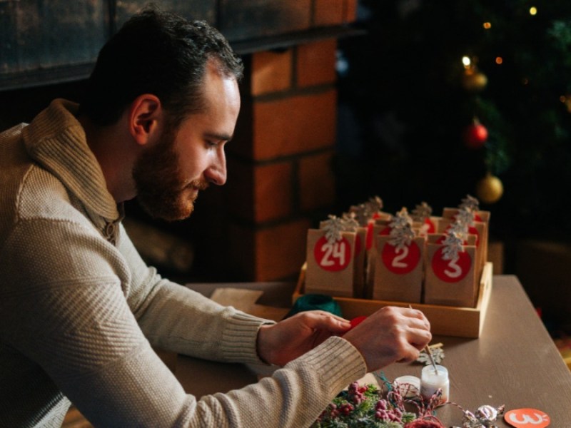 Ein Mann bastelt einen Adventskalender.