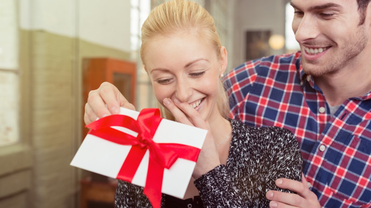 ein Mann überreicht seiner Freundin einen Geschenkgutschein