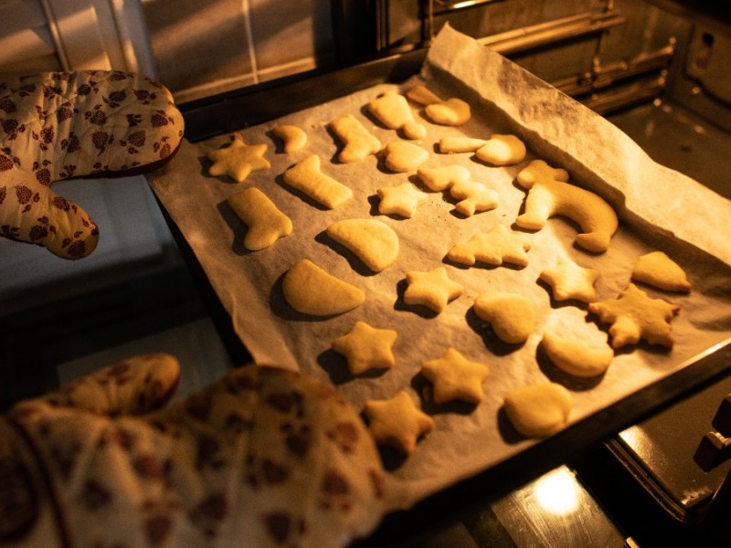 PlÃ¤tzchen backen: Ein Backblech mit PlÃ¤tzchen wird in den Ofen geschoben