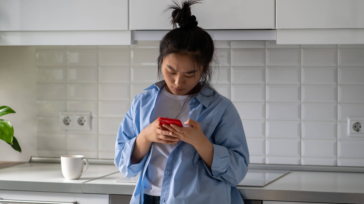 eine junge Frau steht in der KÃ¼che und tippt in ihr Telefon