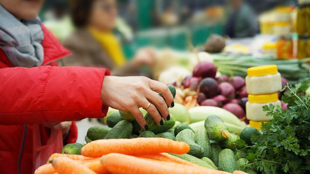 Eine Person greift nach Gemüse an einem Marktstand.