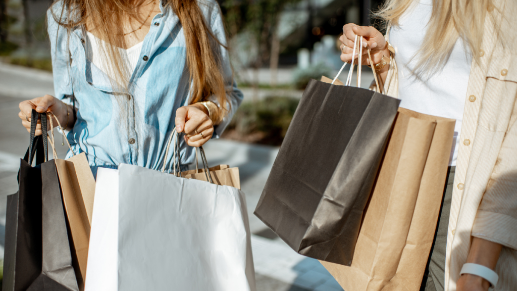 Zwei Frauen tragen viele Einkaufstüten.