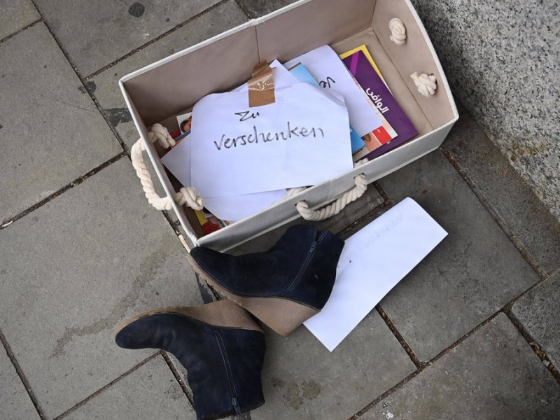 Eine „Zu verschenken“-Kiste am Straßenrand mit Büchern und Schuhen.