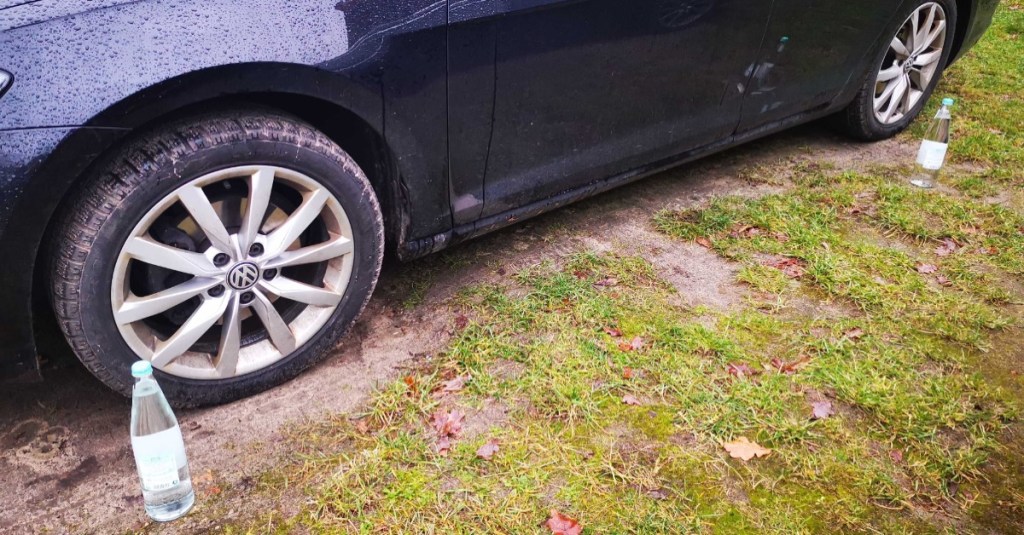 Marder abschrecken: Wasserflaschen stehen an einem schwarzen Auto