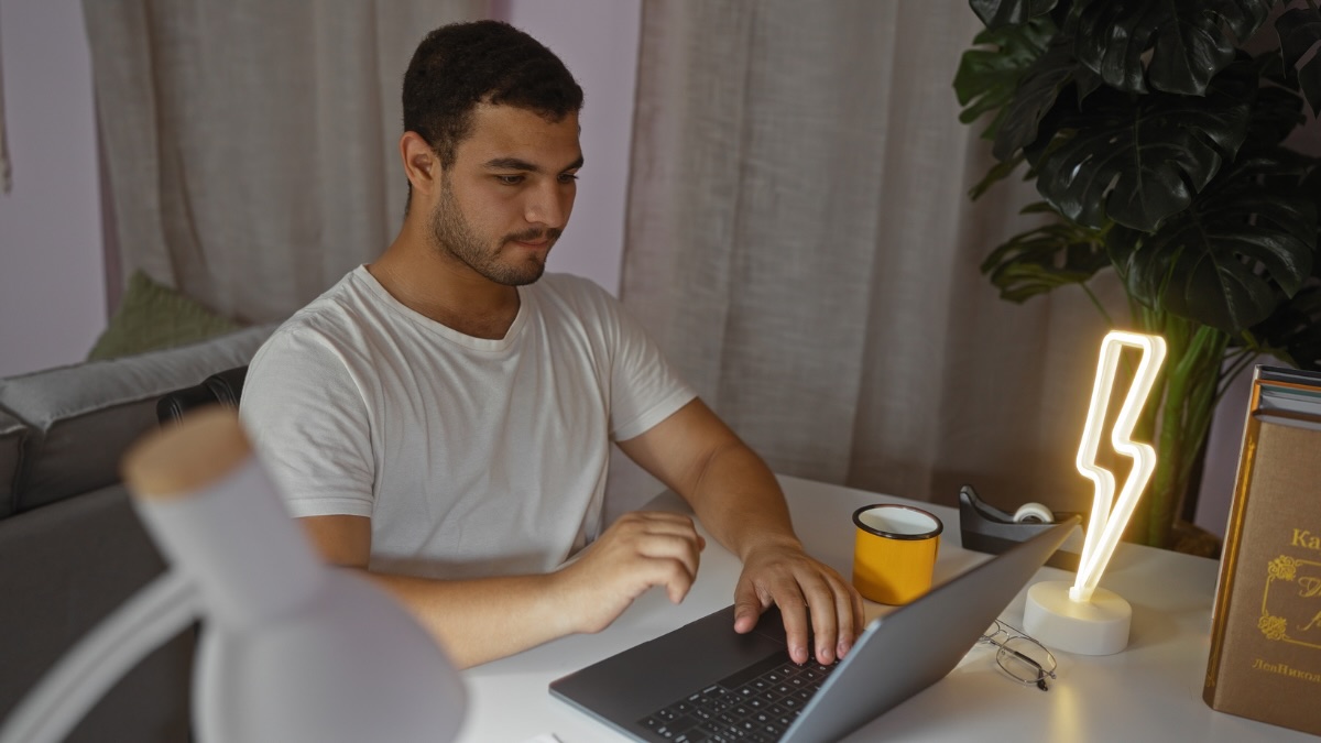 Ein Mann sitzt an einem Schreibtisch am Laptop.