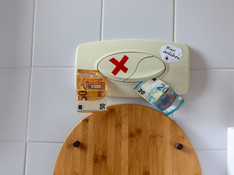 Geldscheine stecken in einer Toilettenspülung.