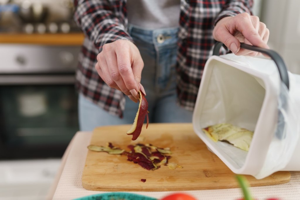 Ein Koch entsorgt Küchenabfälle in einem Bokashi-Eimer.