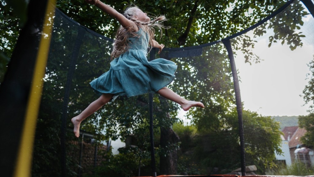 Trampolin reinigen: ein kleines Mädchen springt auf einem Trampolin