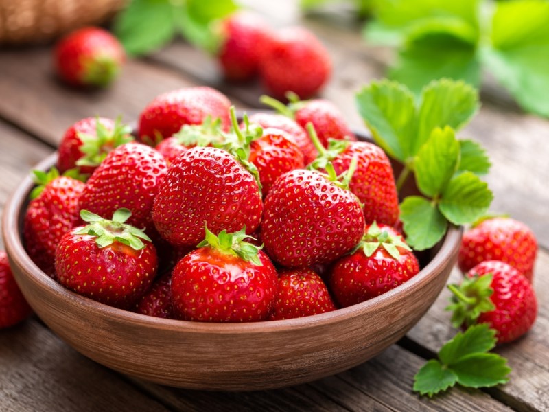 Eine Schale Erdbeeren steht auf dem Tisch.