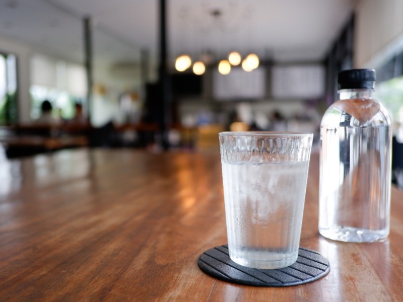 ein Glas und eine Karaffe mit Wasser stehen auf einem Tisch