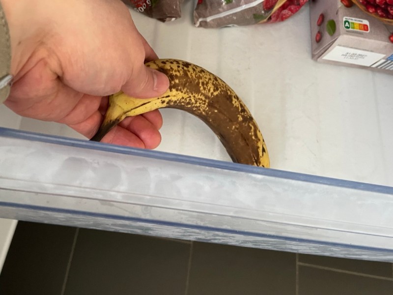 Eine reife Banane wird zum Einfrieren in ein Gefrierfach gelegt.