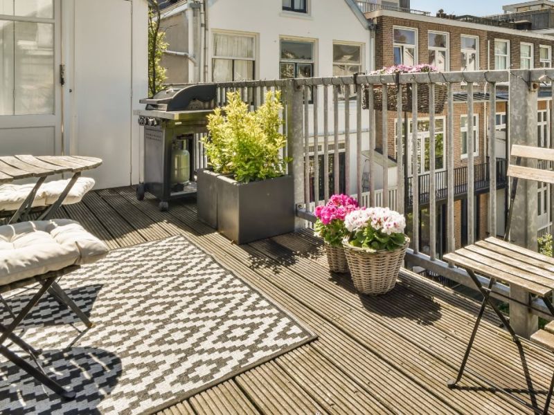 Ein Outdoorteppich auf einem Balkon mit Holzmöbeln und Pflanzen.