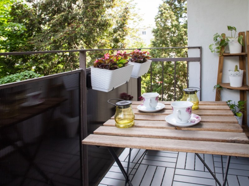 Ein schmaler Balkon mit Balkonmöbeln und Pflanzen.